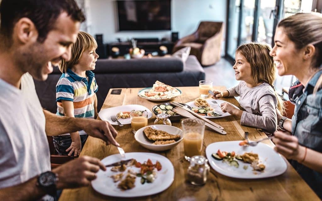 young happy family talking while having lunch GettyImages 1132278686
