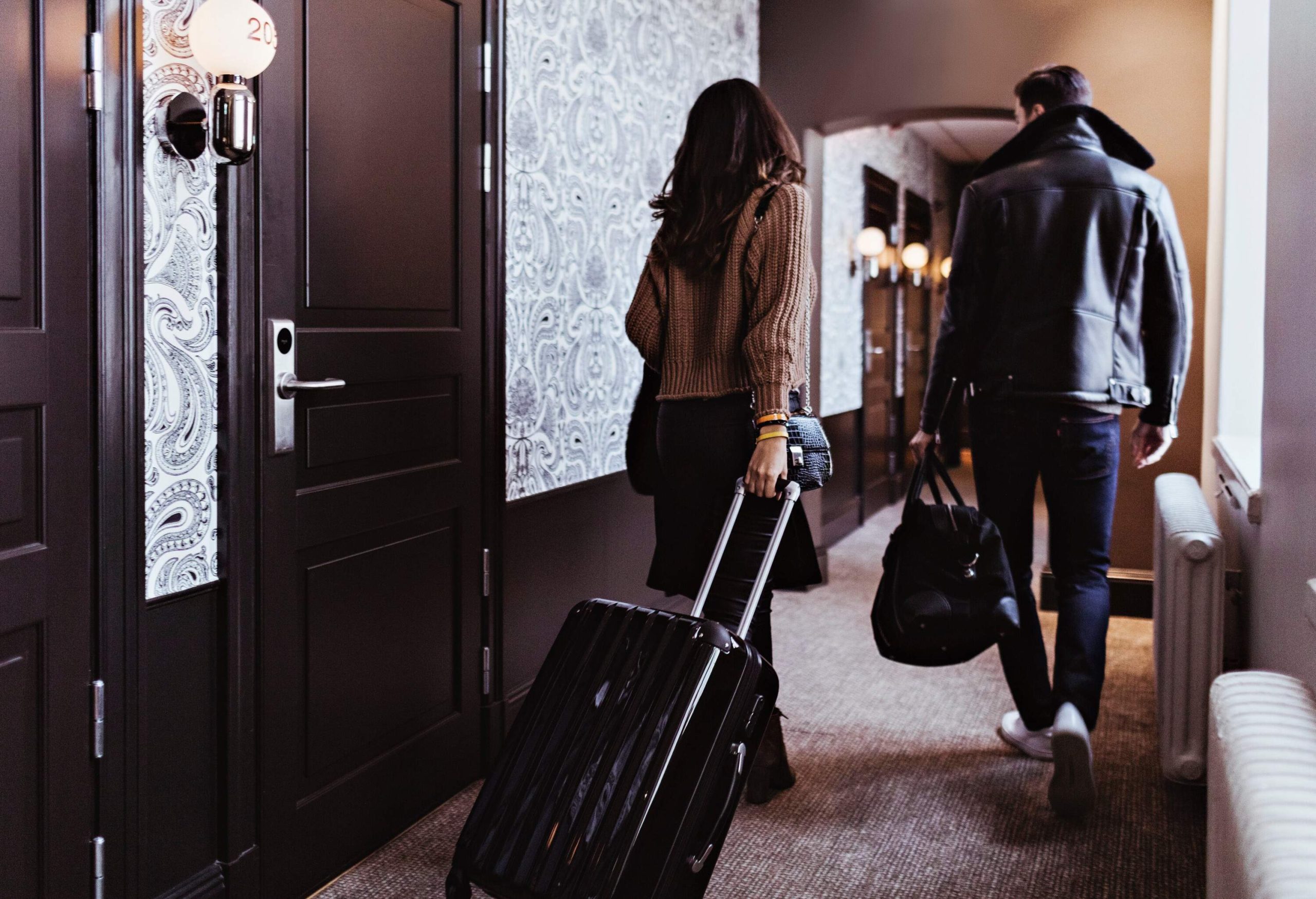 THEME TRAVEL HOTEL CORRIDOR ROOMS PEOPLE COUPLE WALKING LUGGAGE GettyImages 1241453705 scaled 1