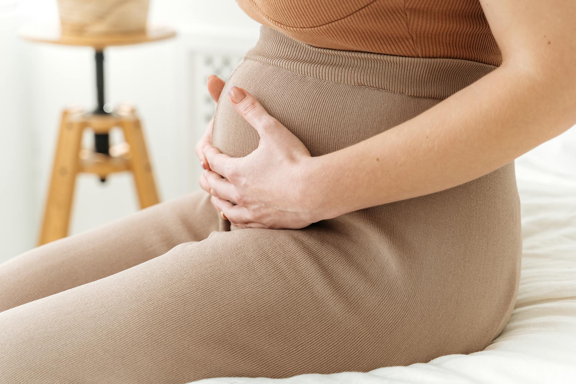 A woman sitting with her hands on her baby bump | Source: Pexels